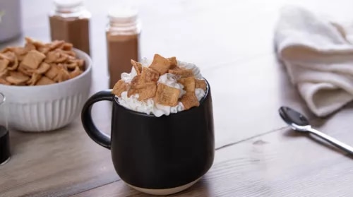 Photograph - black mug of hot chocolate topped with whipped cream and cinnamon marshmallows