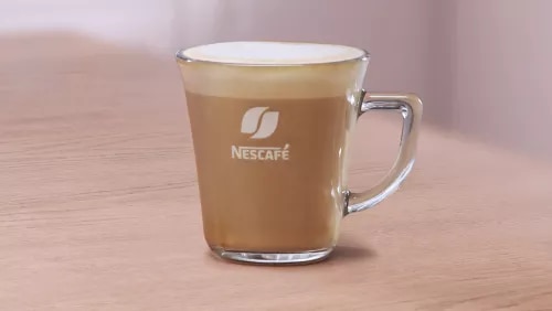 Photograph: clear glass mug with Nescafé logo holding latte with foam on wooden table
