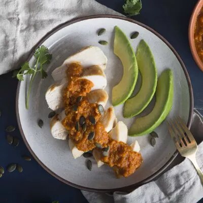 Fotografía: pechuga de pollo en rodajas con salsa y semillas, aguacate en láminas