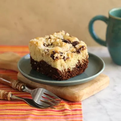 Fotografía: rebanada de pastel de chocolate y crema con chocolate, en plato verde y taza turquesa.