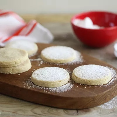 Fotografía de galletas redondas rellenas, espolvoreadas con azúcar sobre tabla de madera