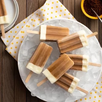 Fotografía: polos helados bicolor (marrón y crema) sobre hielo en plato y servilleta