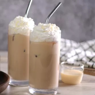 Fotografía de dos vasos de café helado con crema batida y pajillas metálicas