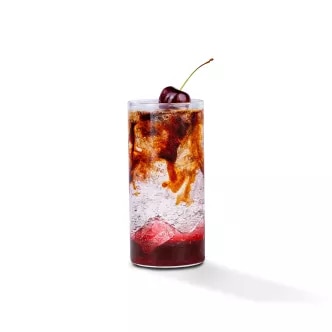 Fotografía: vaso alto con cóctel rojo y blanco, hielo y guinda sobre fondo blanco