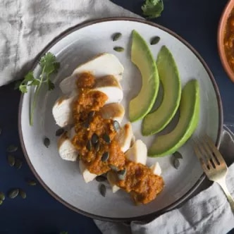 Fotografía: pechuga de pollo en rodajas con salsa y semillas, aguacate en láminas