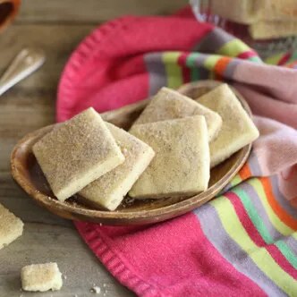 Fotografía de galletas cuadradas caseras en cuenco de madera sobre tela colorida