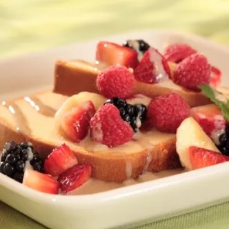 Fotografía de rebanadas de brioche con frambuesas, moras y crema en plato blanco